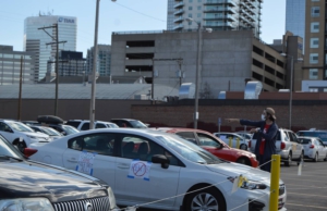 Volunteer directs cars in parking lot gathering place in Denver. Liberation photo. 